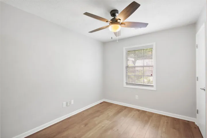 Warm wood-look flooring and a window with blinds define this inviting space.