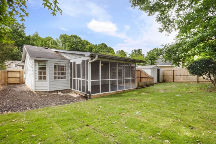 A spacious backyard with a private screened porch and a storage shed.