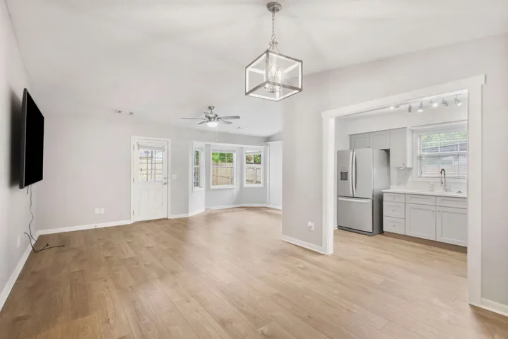 Blonde hardwood floors flow through this light-filled open-concept living area, leading to a modern kitchen.