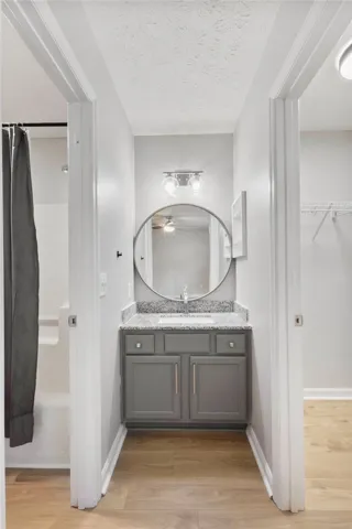 A well-lit bathroom vanity with granite counters, centered between a shower and a closet.