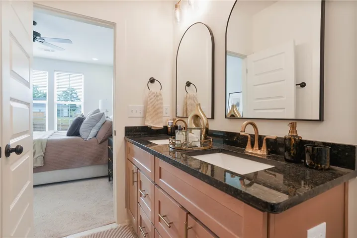 Dual vanity with rich granite counters elevates this primary bath, offering direct access to the bedroom.