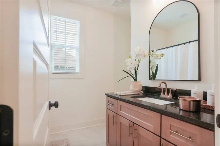Granite countertop vanity with an elegant arched mirror enhances this primary bathroom.