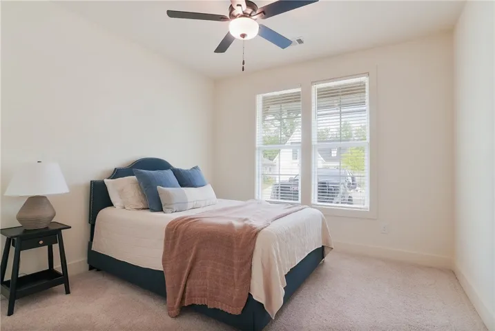 A well-lit bedroom features plush carpeting and abundant natural light.
