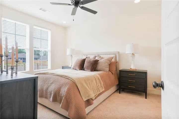 A comforting bedroom space features soft carpet and ample natural light from generous windows.