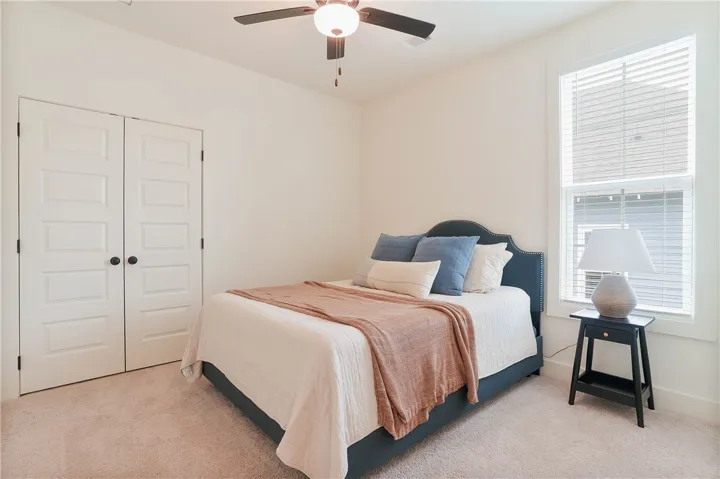A well-lit room with soft carpet and a convenient ceiling fan.