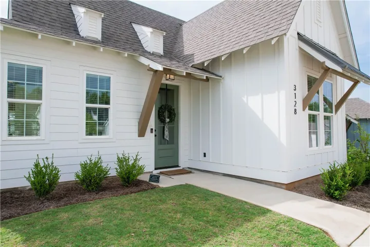 A charming farmhouse-style home showcasing board and batten siding, dormer windows, and a welcoming front entrance.