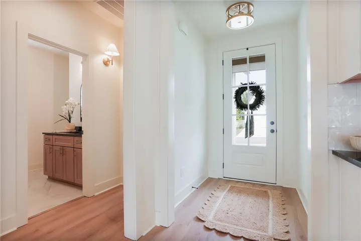 A welcoming entryway with warm wood flooring opens to an adjacent bathroom vanity.