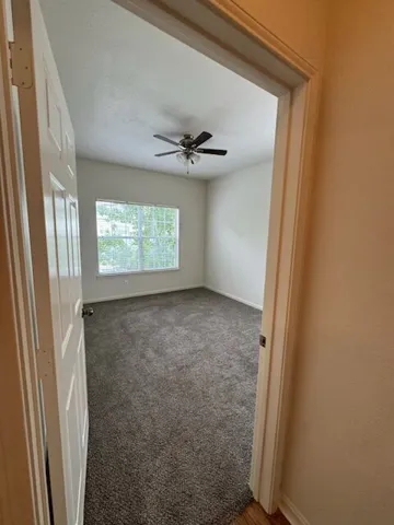 A well-lit bedroom features plush carpeting and a ceiling fan for year-round comfort.