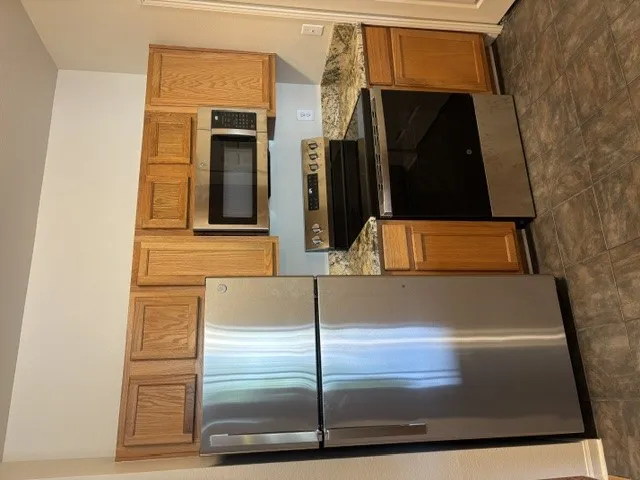 Kitchen showcasing gleaming stainless steel appliances, seamlessly integrated into classic wooden cabinetry.