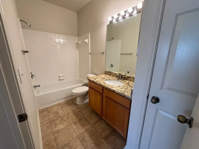 Step into a well-appointed bathroom featuring a tub-shower combination and a vanity with stone counters.