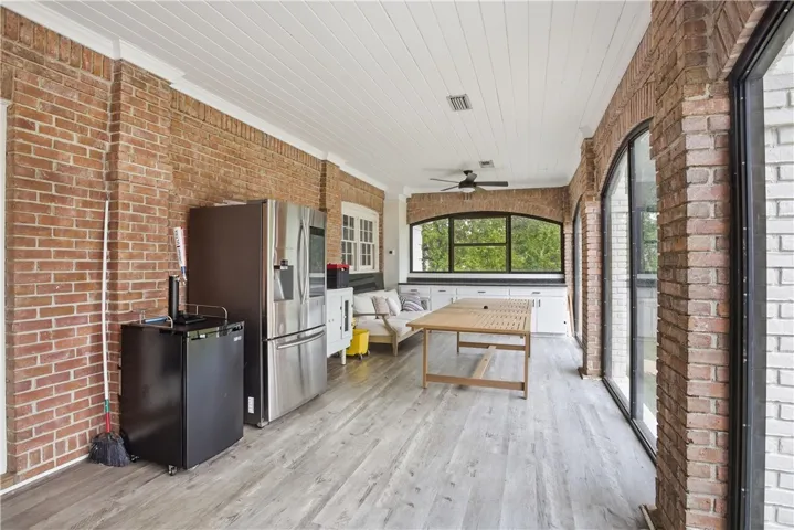 A spacious sunroom with exposed brick and natural light offers generous space for entertaining.