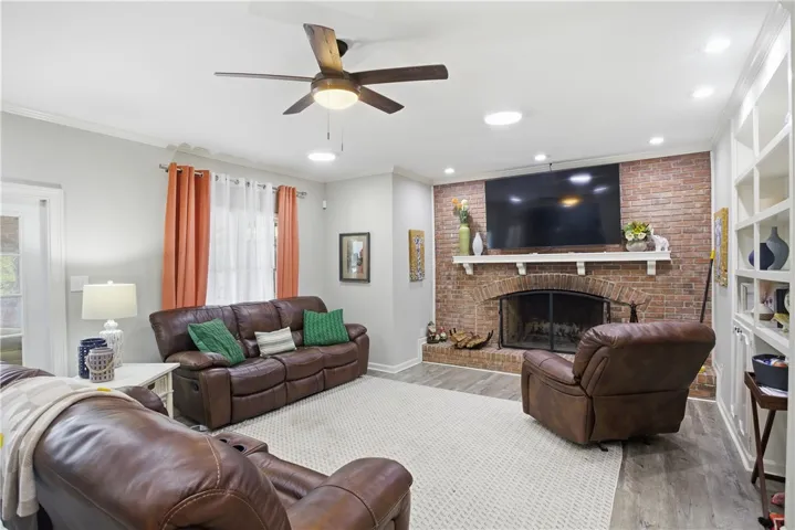 A comforting living room featuring a brick fireplace and built-in shelving, ideal for gathering.