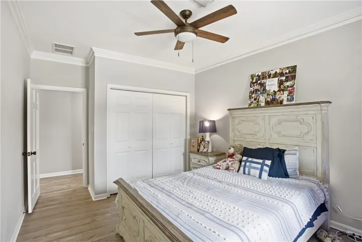 Well-lit sleeping quarters with elegant crown molding and wood-look flooring.