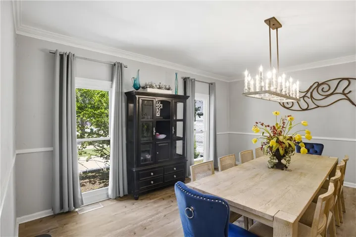 Gather around the large dining table, beneath a stylish rectangular chandelier, perfect for entertaining.