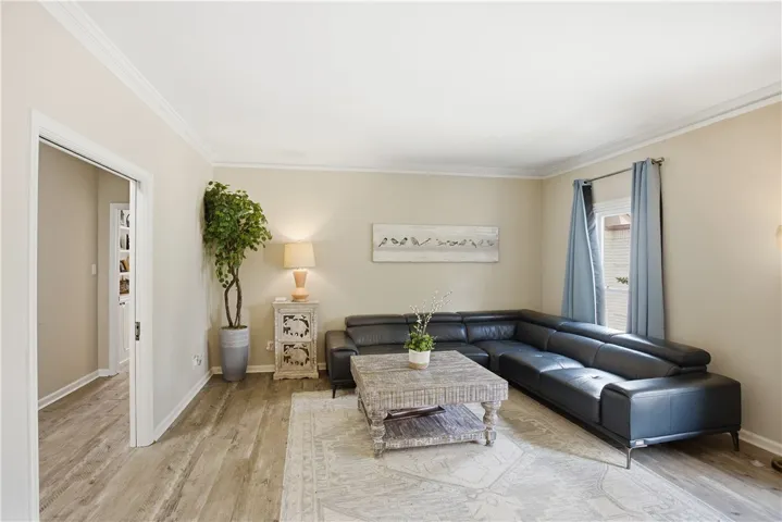 Clean lines and a spacious layout create a comfortable living space with crown molding and light wood flooring.
