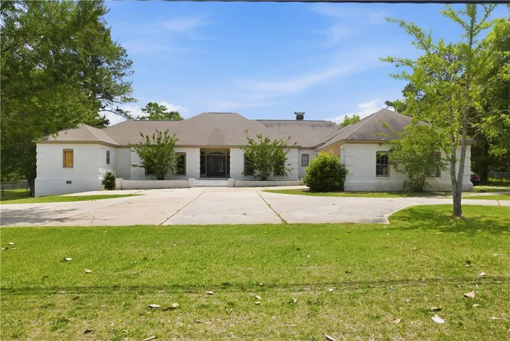 An inviting brick home awaits, nestled amidst verdant landscaping and a sweeping driveway.