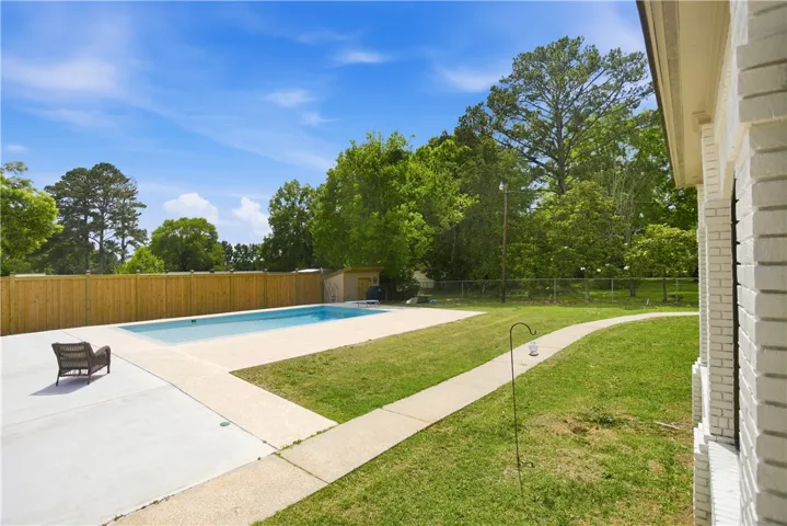 An inviting backyard oasis awaits, complete with a private pool and manicured lawn.