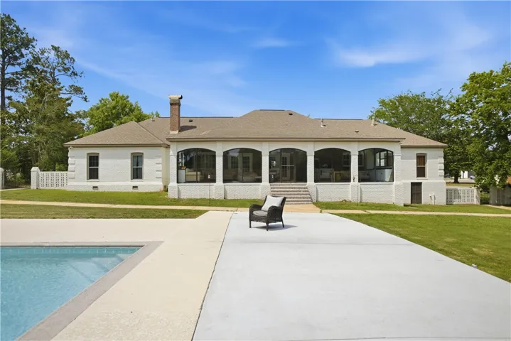 An inviting backyard oasis features a glistening pool and a spacious patio, ideal for outdoor entertaining.
