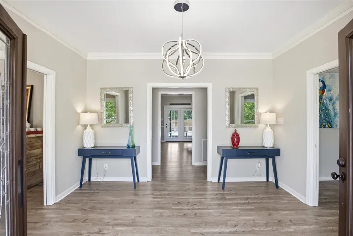 A graceful entry with warm wood-look flooring leads to an inviting living area beyond.