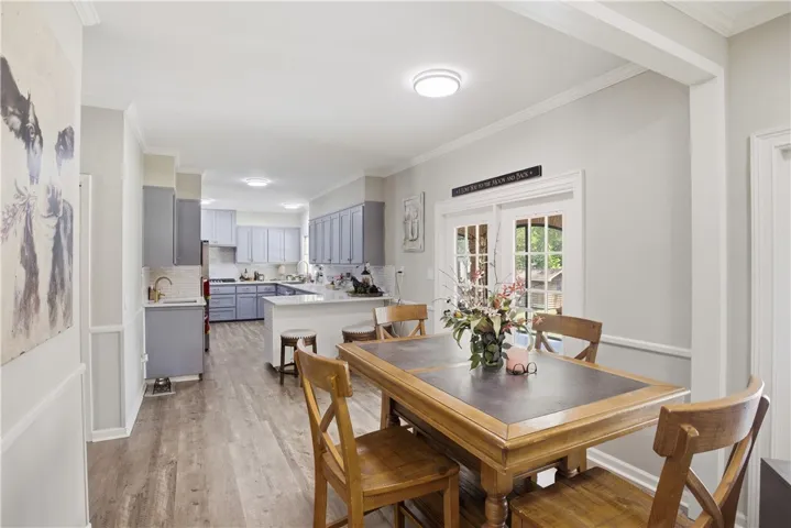 An inviting eat-in kitchen with wood flooring extends to French doors that open to the outdoors.