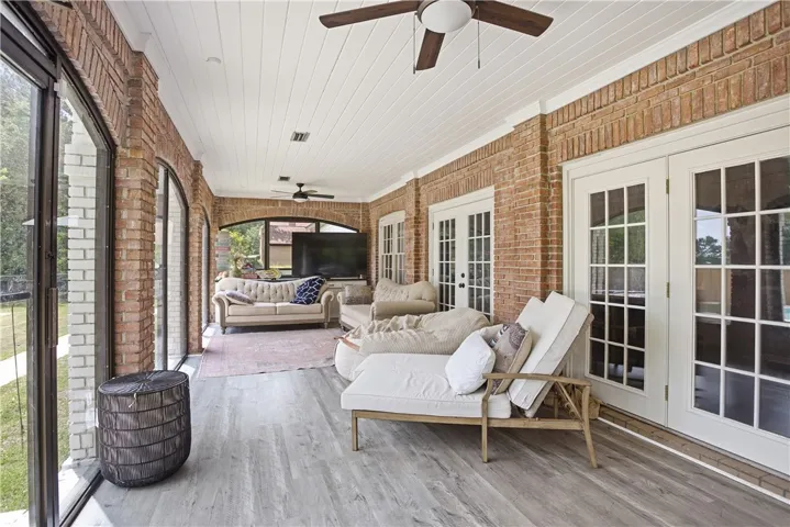 A spacious sunroom with brick walls and large windows offers comfortable lounging.