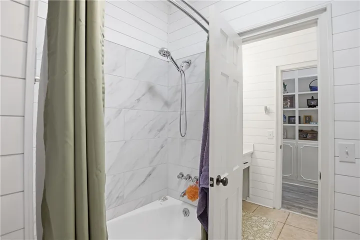 A well-appointed bathroom offers a classic white tub with contemporary tiled shower surround.