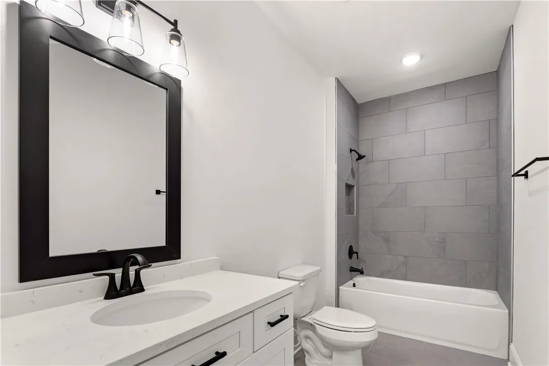 A well-appointed bathroom with contemporary fixtures, including a vanity with a sleek countertop and a tiled shower-tub combination.