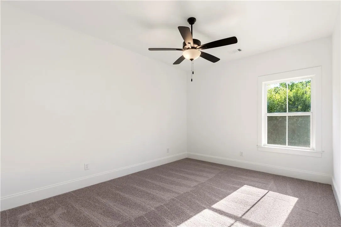 A well-lit bedroom features plush carpeting and a modern ceiling fan for ultimate comfort.
