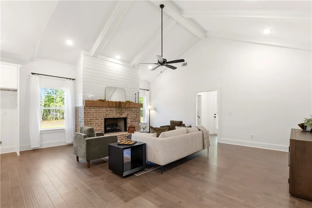 Warm wood flooring extends throughout this generous gathering area with a classic brick fireplace.