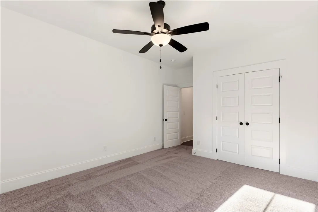 Well-appointed bedroom with a ceiling fan and ample closet space awaits customization.