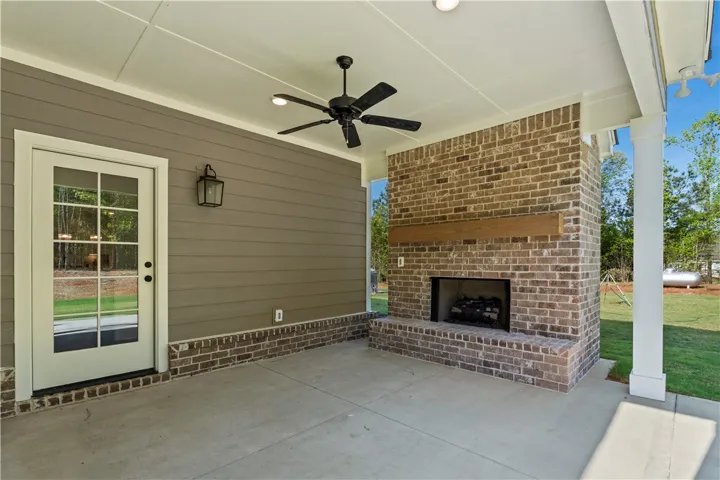 An inviting outdoor patio features a cozy fireplace and a ceiling fan, perfect for year-round comfort.
