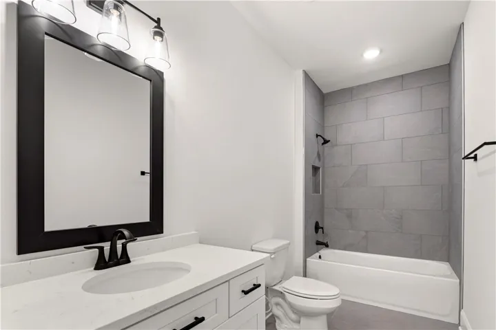 A well-appointed bathroom with contemporary fixtures, including a vanity with a sleek countertop and a tiled shower-tub combination.