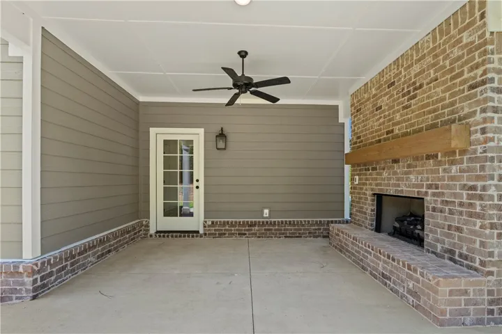 An inviting covered patio featuring a brick fireplace and a ceiling fan for outdoor comfort.