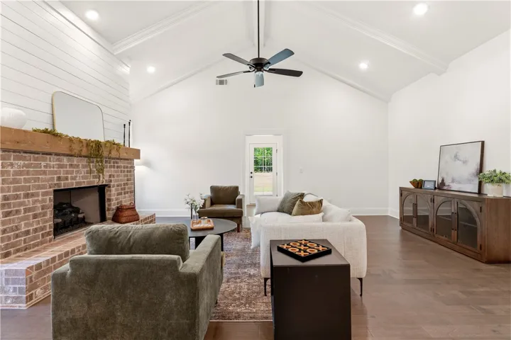 A spacious living room presents vaulted ceilings and an inviting brick fireplace.