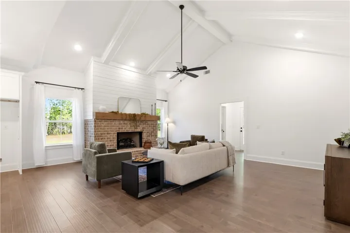 Warm wood flooring extends throughout this generous gathering area with a classic brick fireplace.
