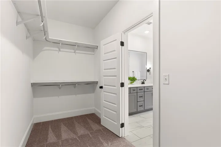 An organized walk-in closet with ample shelving leads to a private bathroom.