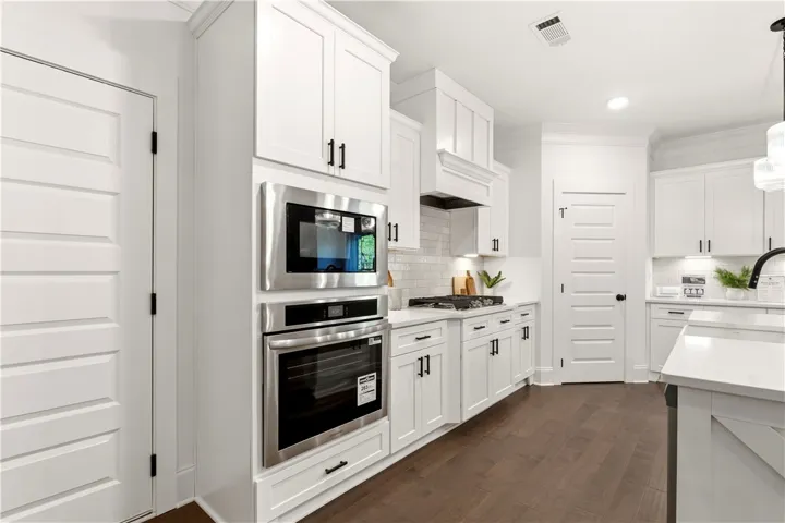 Culinary creations come to life in this kitchen, boasting pristine white cabinetry and dark hardwood flooring.