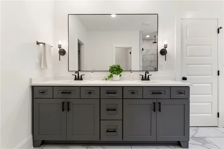 A generously sized dual vanity with ample storage anchors this bright, contemporary primary bathroom.