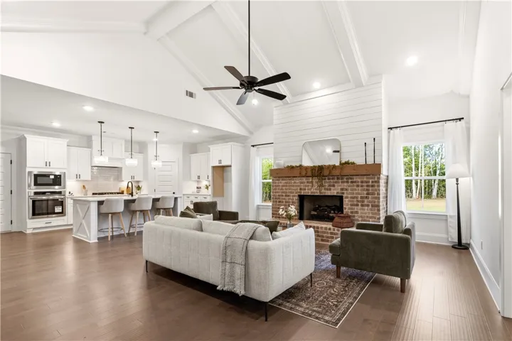 An inviting open-concept living space features a cozy brick fireplace and rich hardwood flooring, seamlessly connecting to a gourmet kitchen.