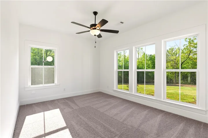 An airy bedroom with verdant outdoor views and soft carpeting welcomes peaceful repose.