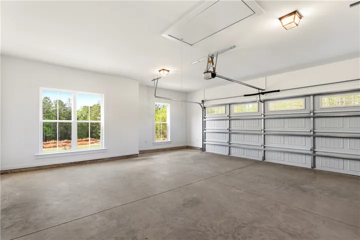 A spacious garage features ample windows for natural illumination and an automated door system for effortless access.