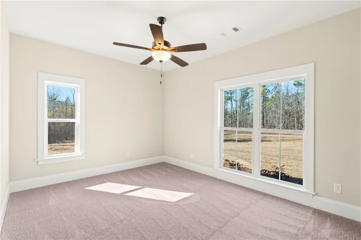 A spacious room offers ample natural light and views of mature trees from multiple windows.