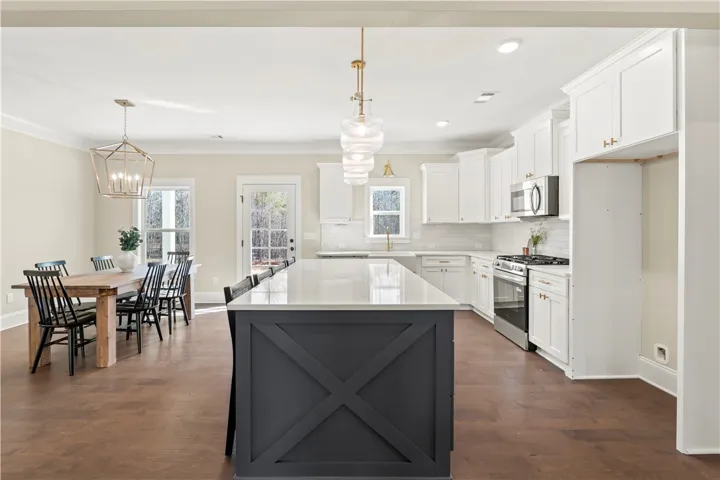 A pristine open-concept kitchen with a grand central island flows into a well-lit dining area, perfect for entertaining.