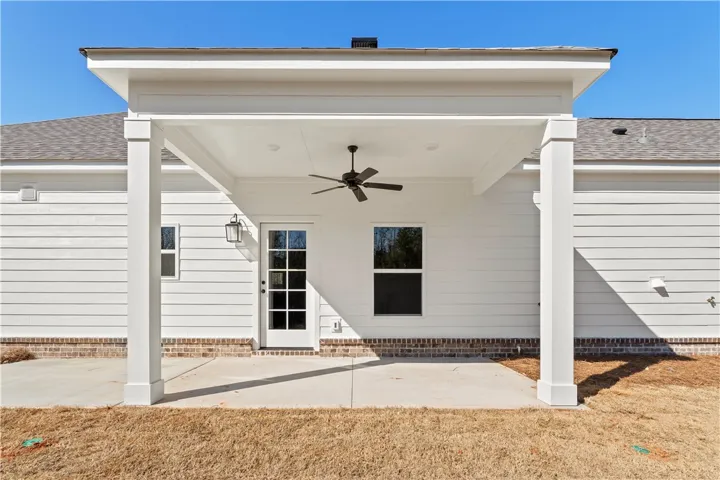 An inviting covered patio with a ceiling fan provides an ideal space for outdoor relaxation.