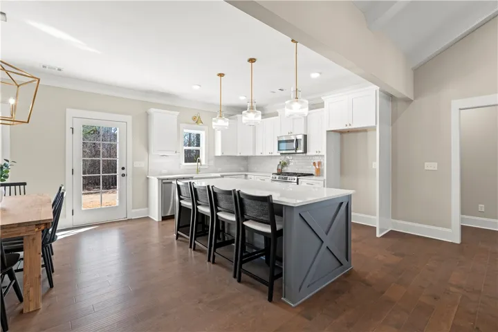 A contemporary chef's kitchen boasts a central island with casual seating and direct backyard access.