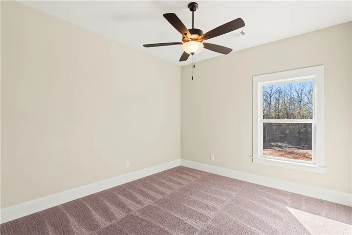 Well-lit room with ample space, offering a quiet retreat and verdant outdoor views.