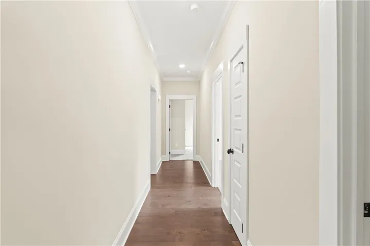 A well-lit corridor with rich hardwood flooring and classic crown molding creates a welcoming passage.