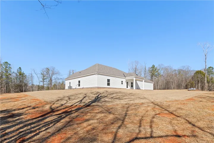 A newly constructed single-story residence is situated on a spacious, dry lot surrounded by a natural wooded landscape.