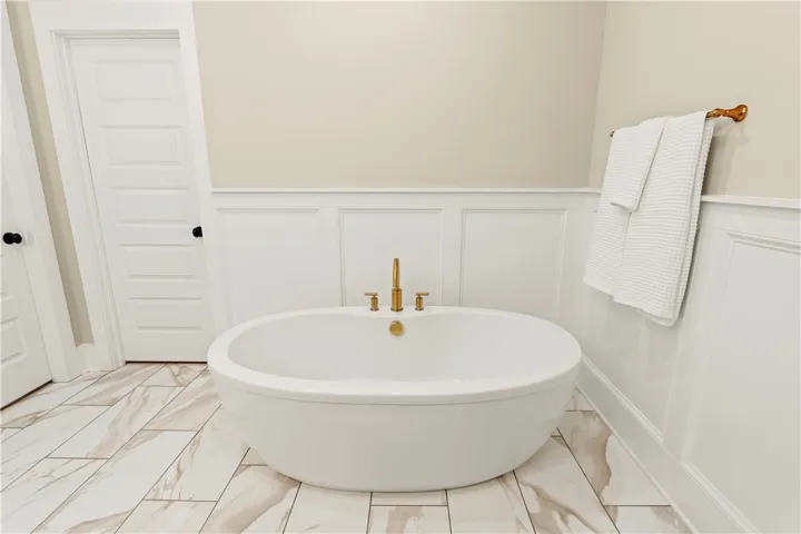Indulge in a tranquil bathing experience with this deep soaking tub, complete with elegant gold fixtures.