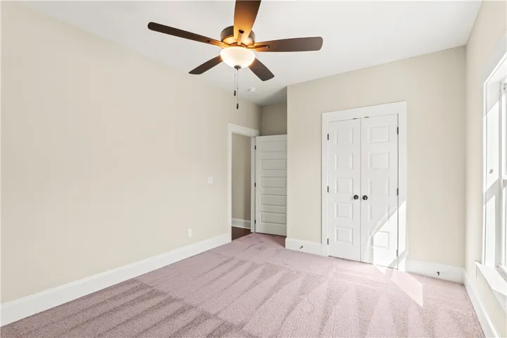 Well-lit interior space with soft carpeting and ceiling fan offers a comfortable ambiance.